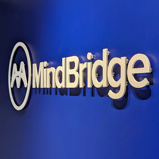 A vibrant blue 3D wall sign with the MindBridge logo prominently displayed in a corporate office setting.